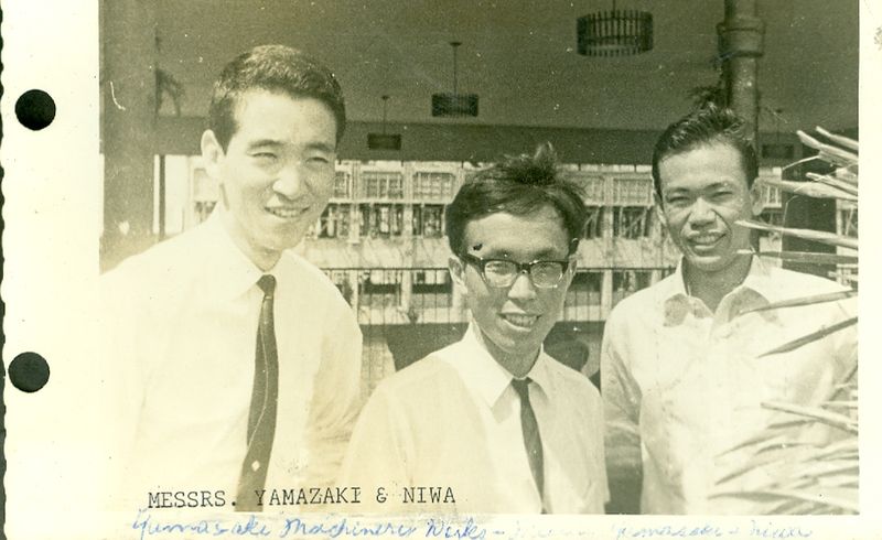 Three men standing together in a showroom lined with shelving